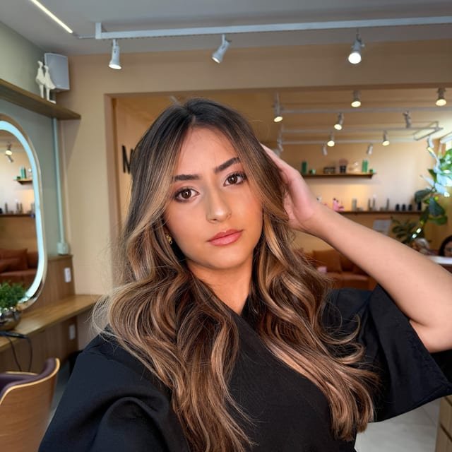 Cliente no salão com morena iluminada e ondas soltas