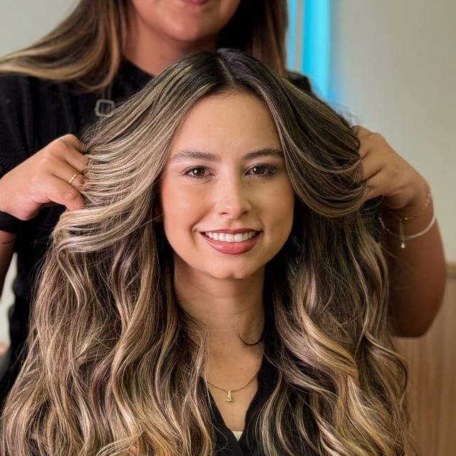 Cliente sorrindo com mechas loiras recém-feitas
