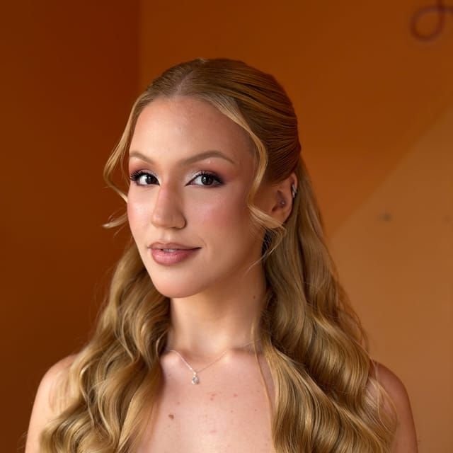 Cliente com loiro iluminado em frente à parede laranja do Moma Hair